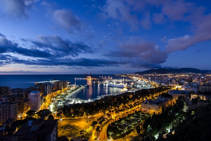 Malaga cityscape at night with harbor and ocean