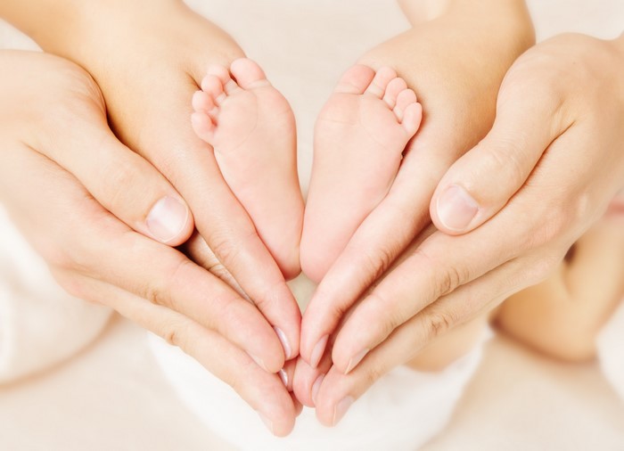 Parents holding baby feet in heart shape