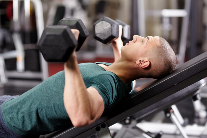 Man doing incline dumbbell press in a gym