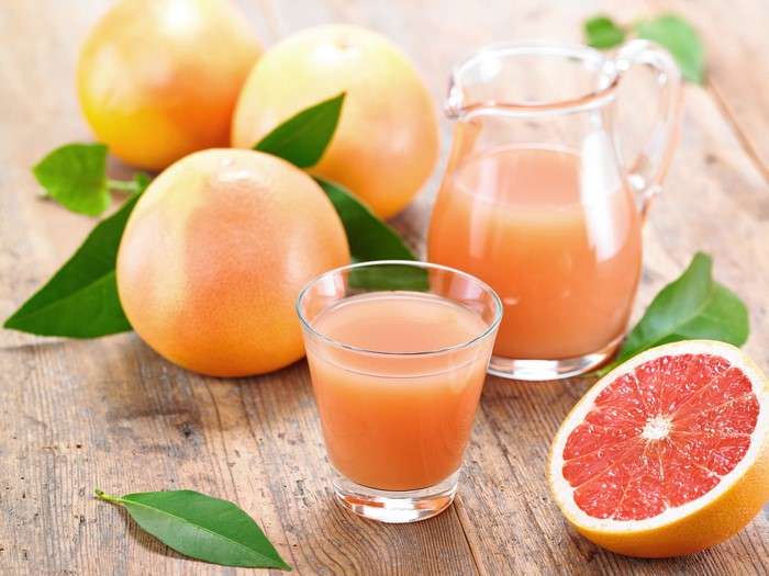 Grapefruit juice in a glass and pitcher with grapefruits