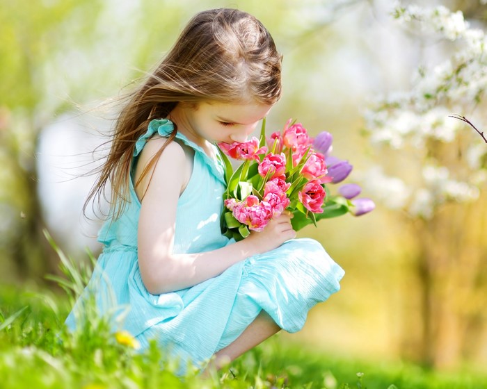 Little girl smelling tulips in spring