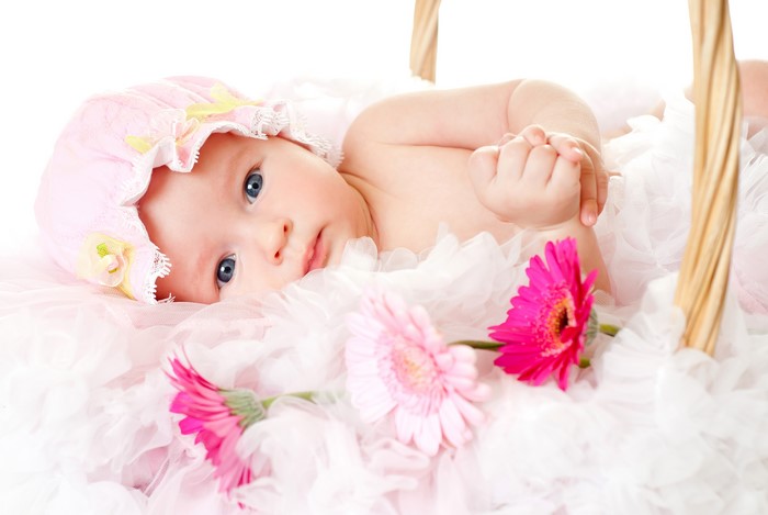 Baby in a basket with Gerberas and a winter hat