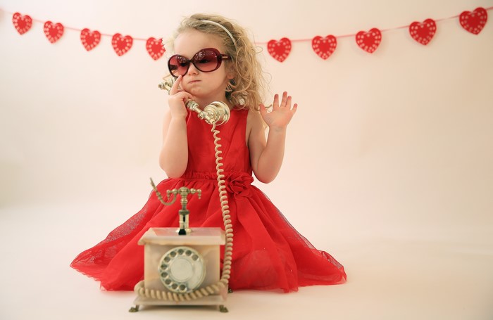 Little girl in red dress with sunglasses on telephone