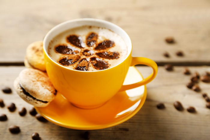 Coffee cup with latte art and macarons on saucer