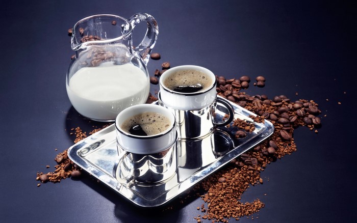 Coffee cups with milk jug and coffee beans