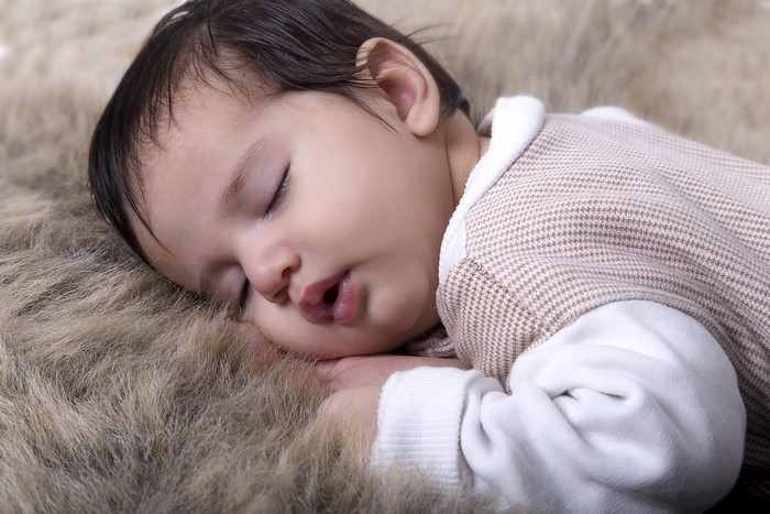 Infant sleeping on a furry rug
