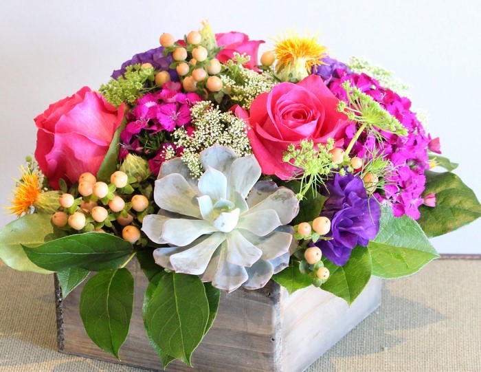 Floral arrangement with roses, succulent, and berries in a wooden box