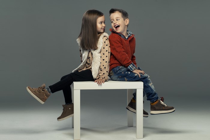 Boy and girl sitting on a white table