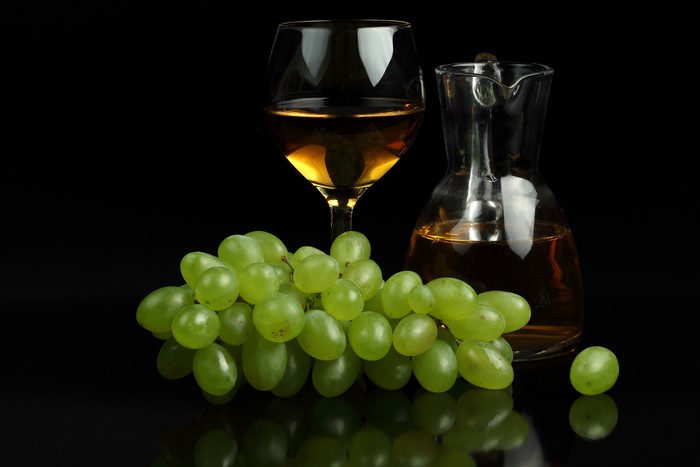 White wine in a glass and jug with green grapes