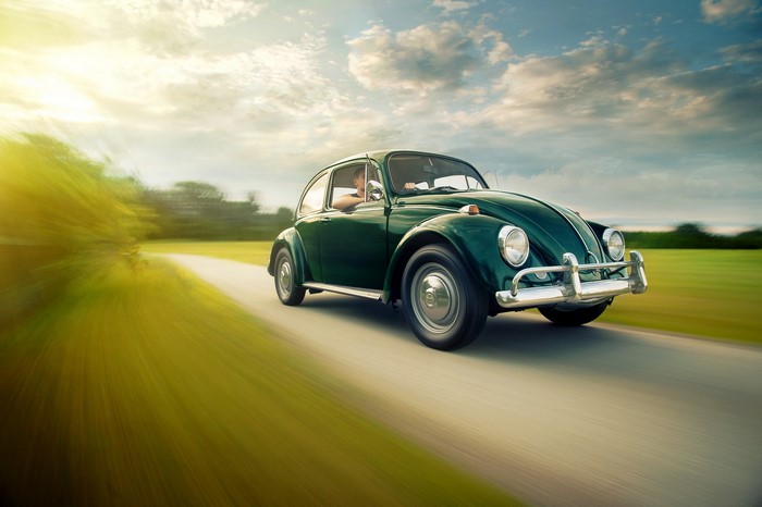 Green Volkswagen Beetle driving on a road
