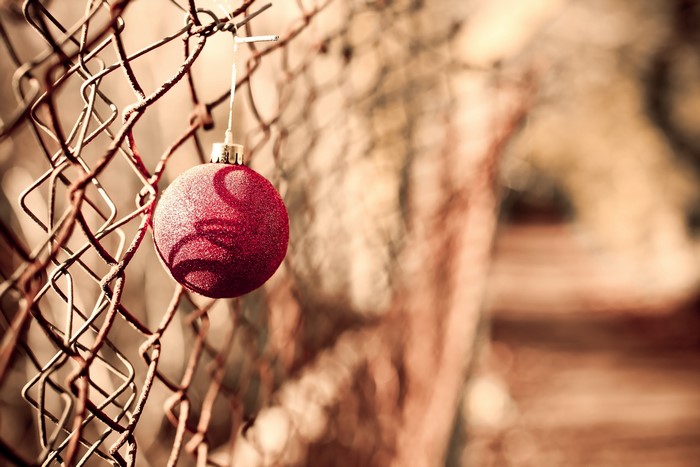 Red Christmas ornament on a chain-link fence