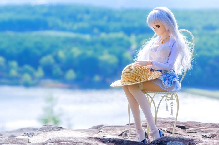 Doll with a straw hat sitting on a chair outdoors