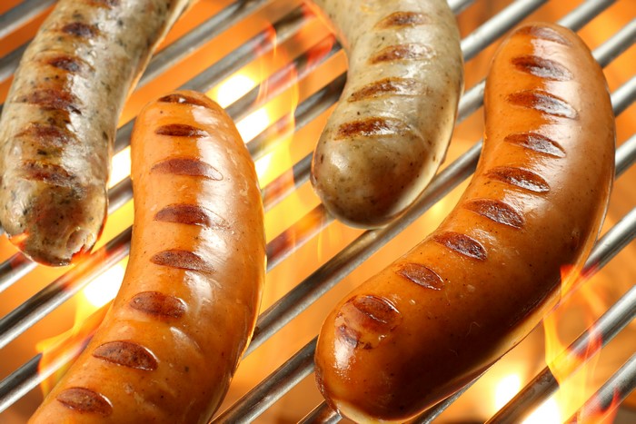 Sausages grilling over flames