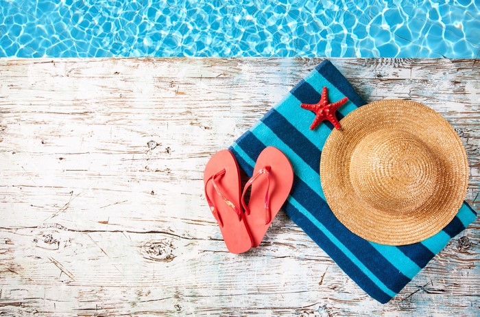 Summer accessories by the pool: starfish, hat, flip-flops, towel