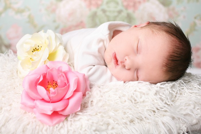 Infant sleeping on fluffy blanket with flowers