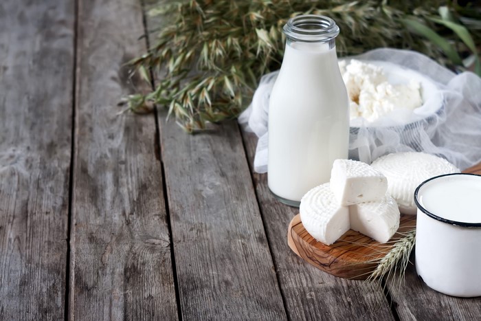 Milk and cheese on wooden planks with wheat