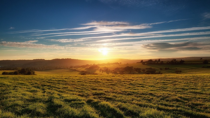 Sunrise over rolling hills and a grassy field