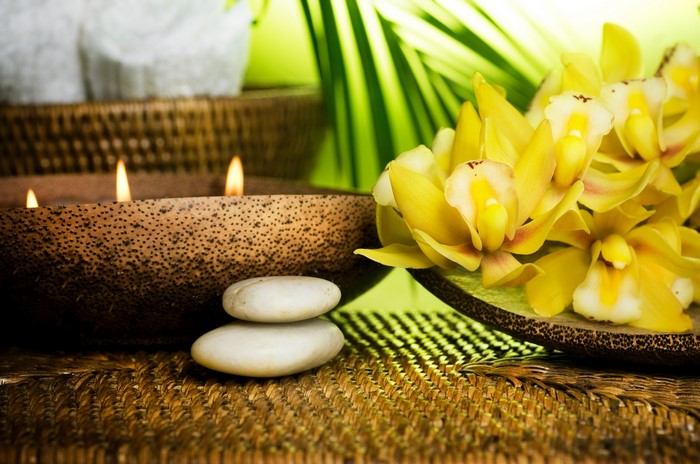 Spa setting with candles, stones, and orchids