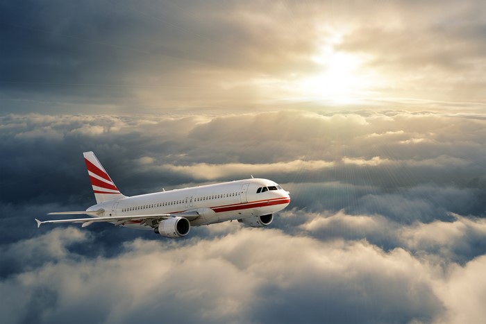 Airplane flying above clouds at sunset