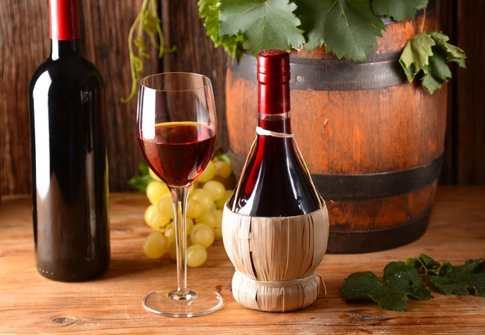 Wine bottles, glass, grapes, and barrel