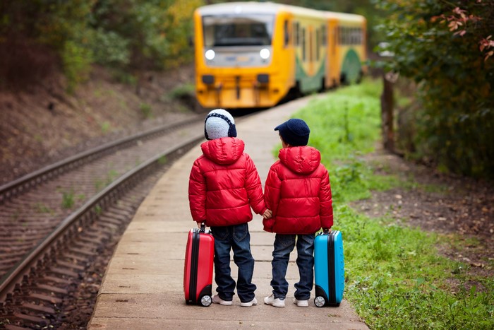 Two boys with suitcases on a train platform