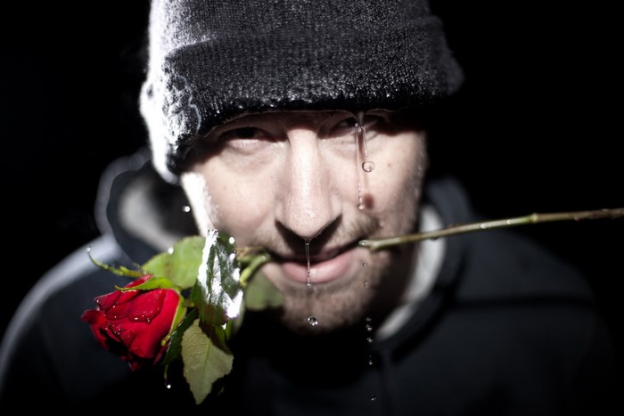 Man in winter hat holding a red rose