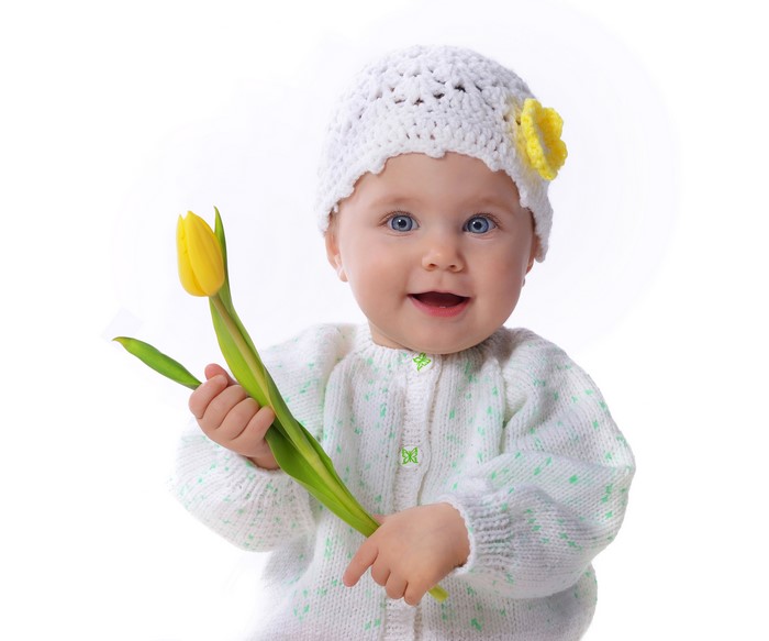 Baby girl in a winter hat holding a tulip
