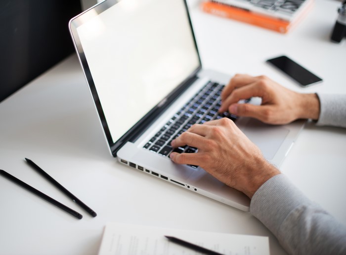 Hands typing on a laptop