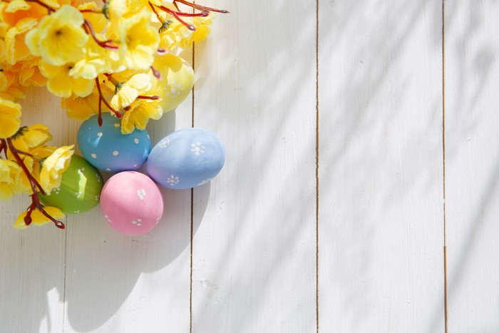 Easter Eggs and Yellow Flowers on White Wood Planks