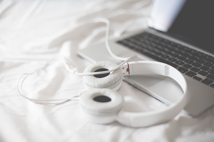 White Headphones and Laptop on White Bedding