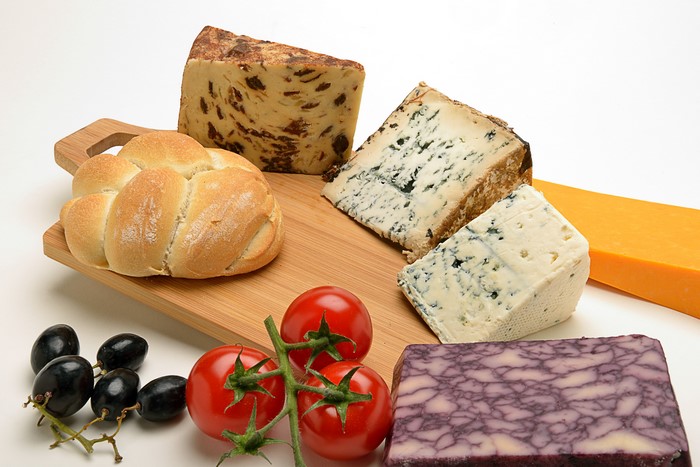 Cheese, Bread, Tomatoes, and Grapes on a Cutting Board