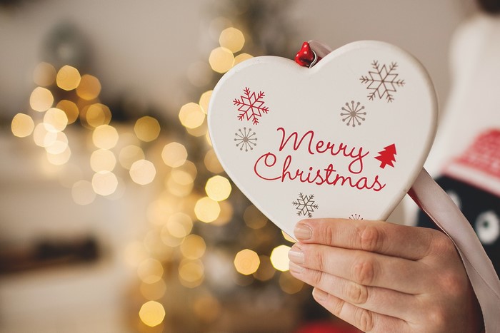 Hand holding a heart-shaped Christmas ornament