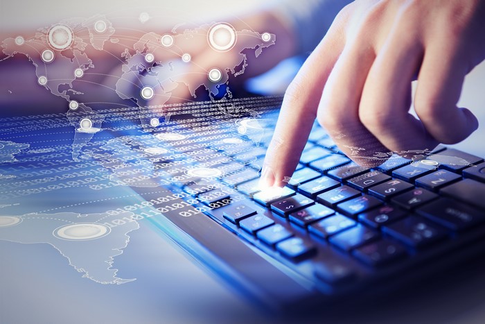 Hand typing on a keyboard with digital overlay