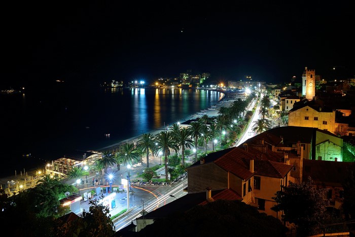 Night view of Savona, Italy coast with palm trees and buildings
