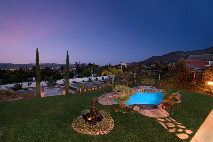 Backyard with pool and fountain at dusk