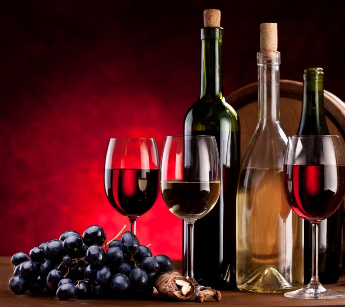 Wine bottles, glasses, grapes, and nuts with barrel