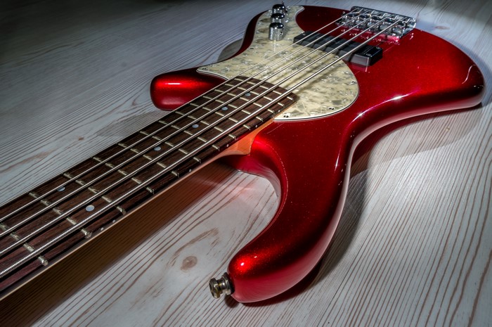 Red bass guitar on a wooden surface