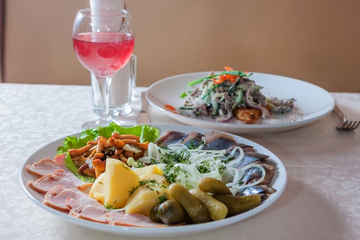 Appetizer platter with ham, potatoes, mushrooms, herring, and pickles