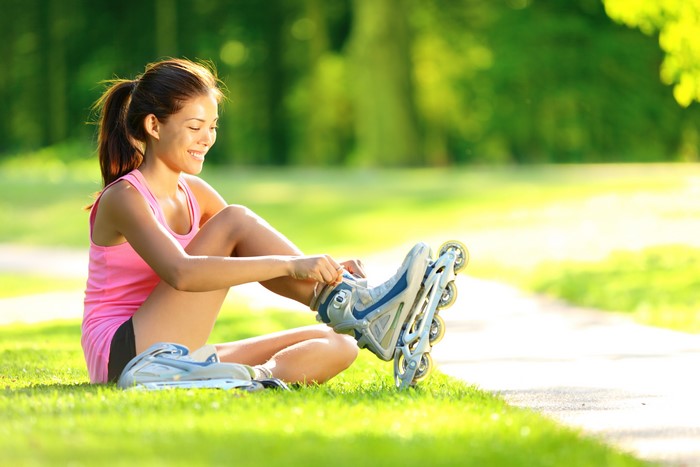 Woman tying roller skates in a park