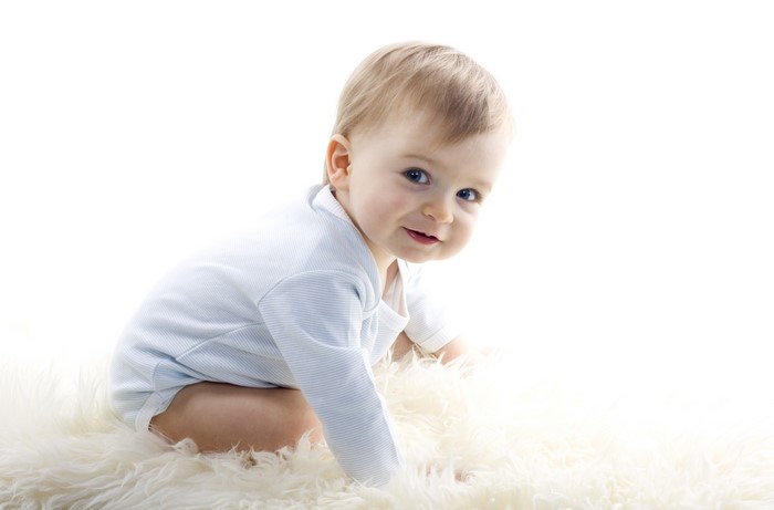 Infant in a blue striped onesie on a white rug