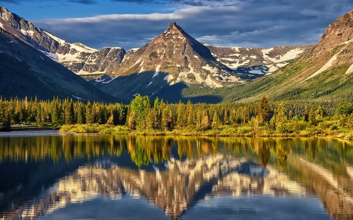 Mountain lake reflection with pine trees and snow-capped peaks