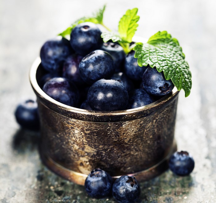 Blueberries in a metal bowl with mint leaves
