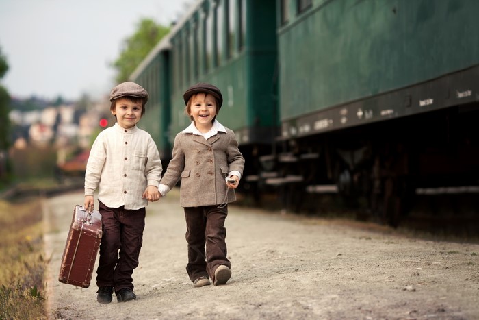 Two boys with suitcase at train station
