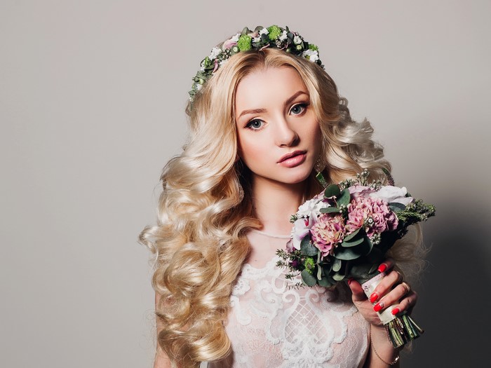 Blonde bride with curly hair and flower crown holding bouquet