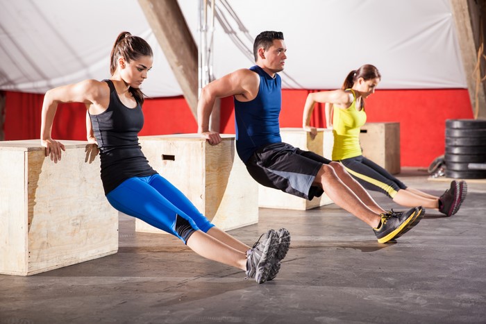 People doing box dips in a gym