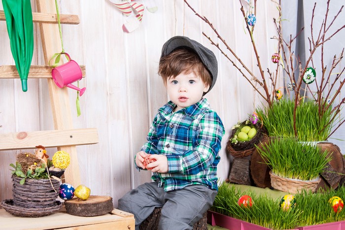 Boy in Easter-themed setting with grass and eggs
