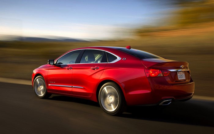 Red Chevrolet Impala driving on a road