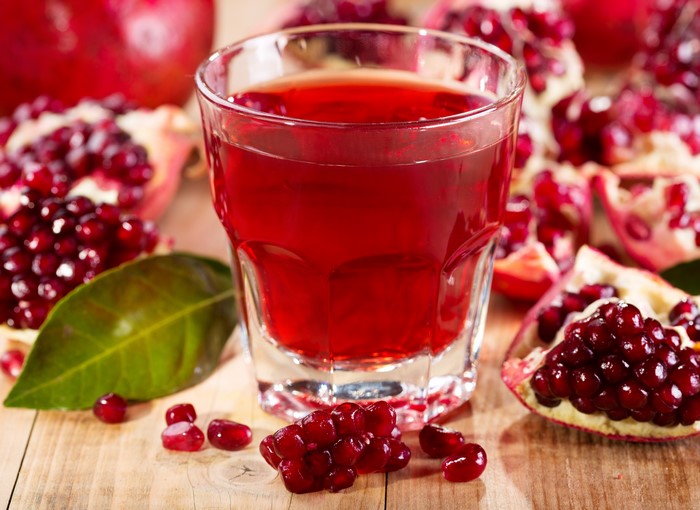 Pomegranate juice in a highball glass with pomegranates
