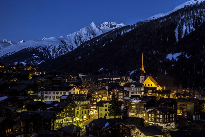 Village at the foot of snow-capped mountains at night