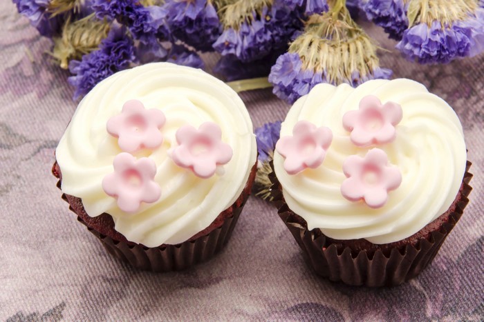 Two red velvet cupcakes with pink flowers